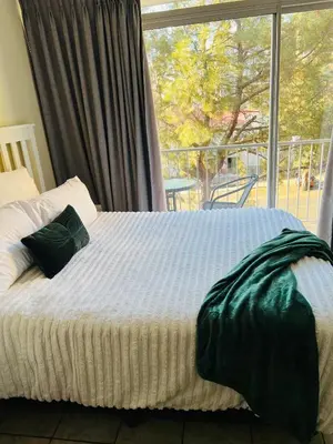 a bed in a bedroom with a large window at Mbizo Cozy Retreat 409 in Pretoria