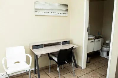 a room with a desk with a chair and a toilet at Mbizo Cozy Retreat 409 in Pretoria