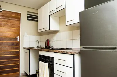 a kitchen with white cabinets and a stainless steel refrigerator at Mbizo Cozy Retreat 409 in Pretoria