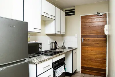 a small kitchen with white cabinets and a refrigerator at Mbizo Cozy Retreat 409 in Pretoria