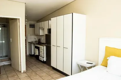 a bedroom with a white cabinet and a kitchen at Mbizo Cozy Retreat 409 in Pretoria
