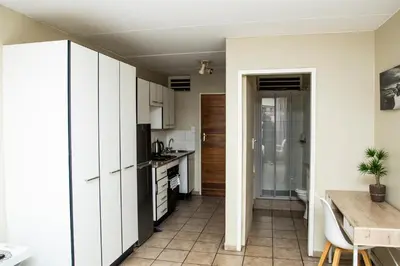 a small kitchen with white cabinets and a table at Mbizo Cozy Retreat 409 in Pretoria