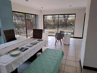 a dining room with a table and chairs and windows at Sentinel Condo in Pretoria