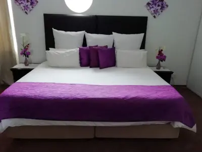a purple and white bed with purple sheets and pillows at Sentinel Condo in Pretoria