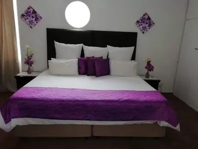 a bedroom with a large bed with purple sheets and pillows at Sentinel Condo in Pretoria