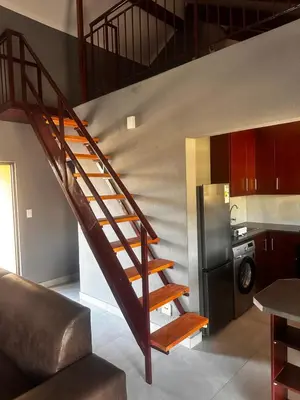 a staircase in a living room with a kitchen at 53 Bela-Bela Pendleberry Grove Holiday Resort Unit 53 in Bela-Bela