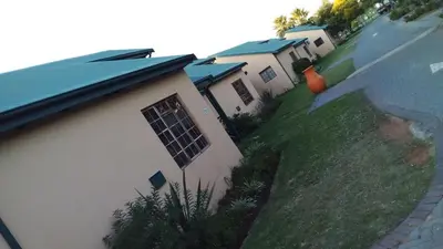 a house with a grassy yard next to a building at 53 Bela-Bela Pendleberry Grove Holiday Resort Unit 53 in Bela-Bela
