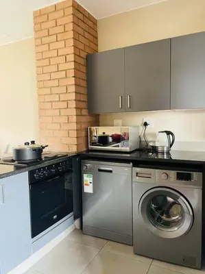 a kitchen with a washing machine and a washer at Waterfall Ridge Premium Apartments in Midrand