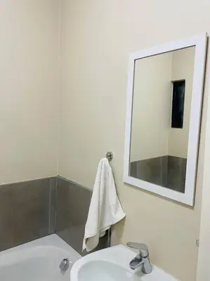a bathroom with a sink and a mirror at Waterfall Ridge Premium Apartments in Midrand