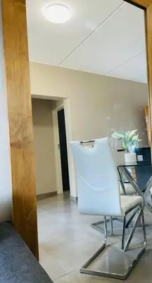 a room with a white chair in a room at Waterfall Ridge Premium Apartments in Midrand