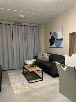 a living room with a black couch and a table at Waterfall Ridge Premium Apartments in Midrand
