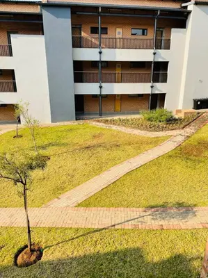 a building with a tree in the middle of a yard at Waterfall Ridge Premium Apartments in Midrand