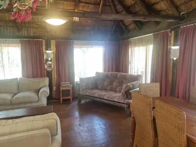 a living room with a couch and a table at Wooden Log House in Bela-Bela