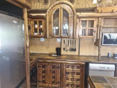 a kitchen with wooden cabinets and utensils at Wooden Log House in Bela-Bela
