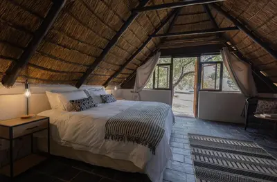 a bedroom with a bed and a large window at Amy's Camp at the Kevin Richardson Foundation in Dinokeng Game Reserve
