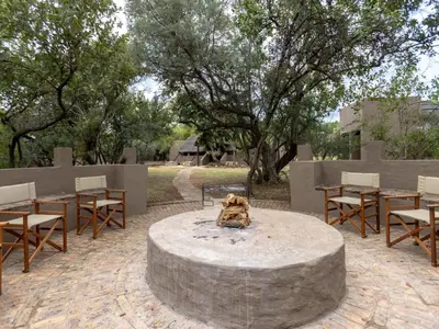 a stone fire pit with chairs and tables at Amy's Camp at the Kevin Richardson Foundation in Dinokeng Game Reserve