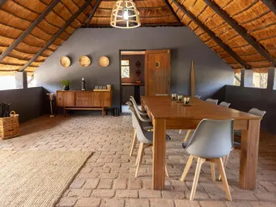 a dining room with a wooden table and chairs at Amy's Camp at the Kevin Richardson Foundation in Dinokeng Game Reserve