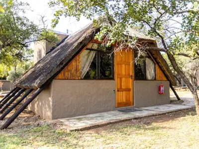 a small house with a thatched roof at Amy's Camp at the Kevin Richardson Foundation in Dinokeng Game Reserve