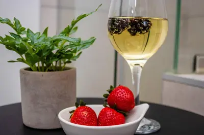 a glass of wine and strawberries on a table at Urban Luxe by Jules, Ellipse, Waterfall in Midrand