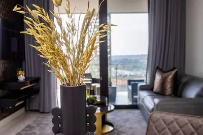 a living room with a vase with plants in it at Urban Luxe by Jules, Ellipse, Waterfall in Midrand