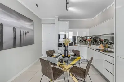 a dining room with a glass table and chairs at Urban Luxe by Jules, Ellipse, Waterfall in Midrand