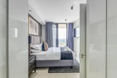 a bedroom with a bed and a large window at Urban Luxe by Jules, Ellipse, Waterfall in Midrand