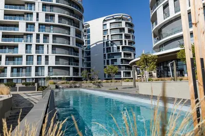 a swimming pool in front of two tall buildings at Urban Luxe by Jules, Ellipse, Waterfall in Midrand