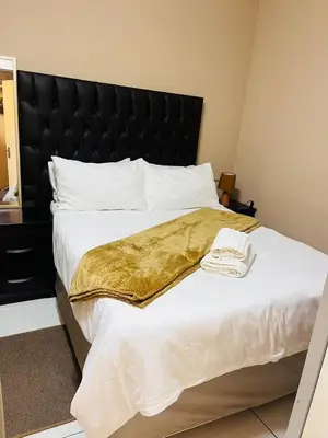 a large bed with a gold blanket on it at Palm Rest in Pretoria