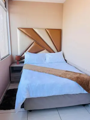 a bed with a wooden headboard in a room at Palm Rest in Pretoria