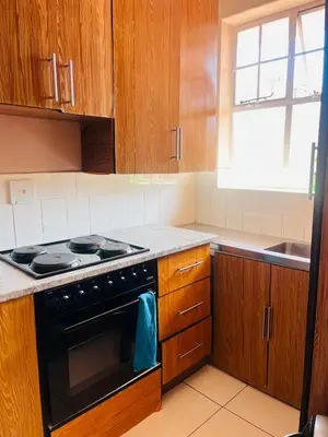 a kitchen with wooden cabinets and a stove top oven at Palm Rest in Pretoria