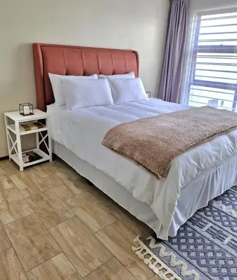 a bedroom with a large bed and a night stand at Eden Breeze Hartbeespoort in Hartbeespoort