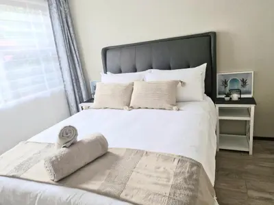 a bedroom with a white bed with a large window at Eden Breeze Hartbeespoort in Hartbeespoort