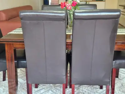 a table with black leather chairs and a vase with flowers at Eden Breeze Hartbeespoort in Hartbeespoort