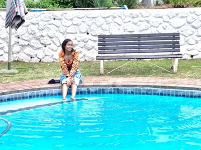 a woman sitting on a bench next to a swimming pool at Eden Breeze Hartbeespoort in Hartbeespoort
