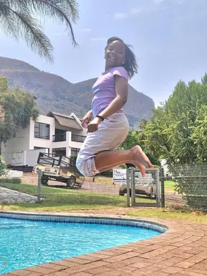 a woman jumping in the air next to a pool at Eden Breeze Hartbeespoort in Hartbeespoort