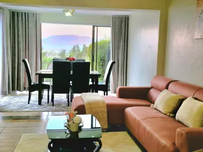 a living room with a couch and a table at Eden Breeze Hartbeespoort in Hartbeespoort