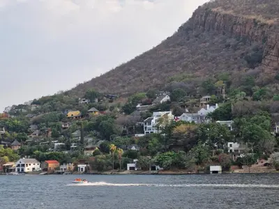 a boat in the water in front of a mountain at Eden Breeze Hartbeespoort in Hartbeespoort