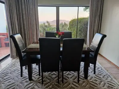 a dining room with a table and chairs and a window at Eden Breeze Hartbeespoort in Hartbeespoort