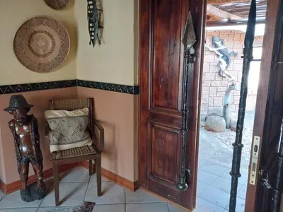 a room with a chair and a wooden door at Assegai Lodge in Moheme