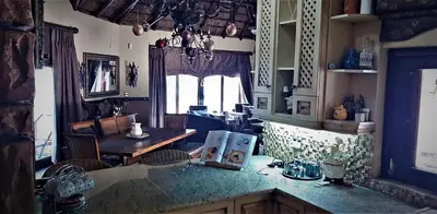 a kitchen with a counter and a table and a window at Assegai Lodge in Moheme