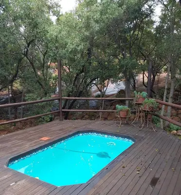 a small pool on a deck with a table and chairs at Assegai Lodge in Moheme