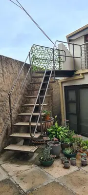 a set of stairs next to a house with potted plants at Upstairs R-1 Self-Catering Unit in White River
