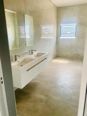 a white bathroom with a sink and a mirror at Zinnia house in Midrand