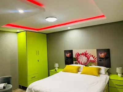 a bedroom with green walls and a bed with yellow pillows at Debreeze guest lodge in Malelane