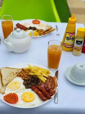 a plate of breakfast food with eggs bacon and french fries at Debreeze guest lodge in Malelane