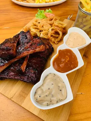 a plate of food with ribs and dips on a table at Debreeze guest lodge in Malelane