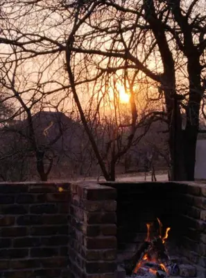 a fire pit with the sunset in the background at Erdvark Bosbreek in Marloth Park