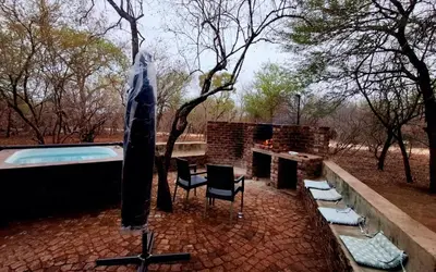 a patio with a swimming pool and a table and chairs at Erdvark Bosbreek in Marloth Park