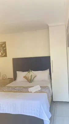 a bedroom with a large bed with white sheets at Giraffe camel in Phalaborwa