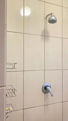 a shower with a shower head on a white tile wall at Giraffe camel in Phalaborwa